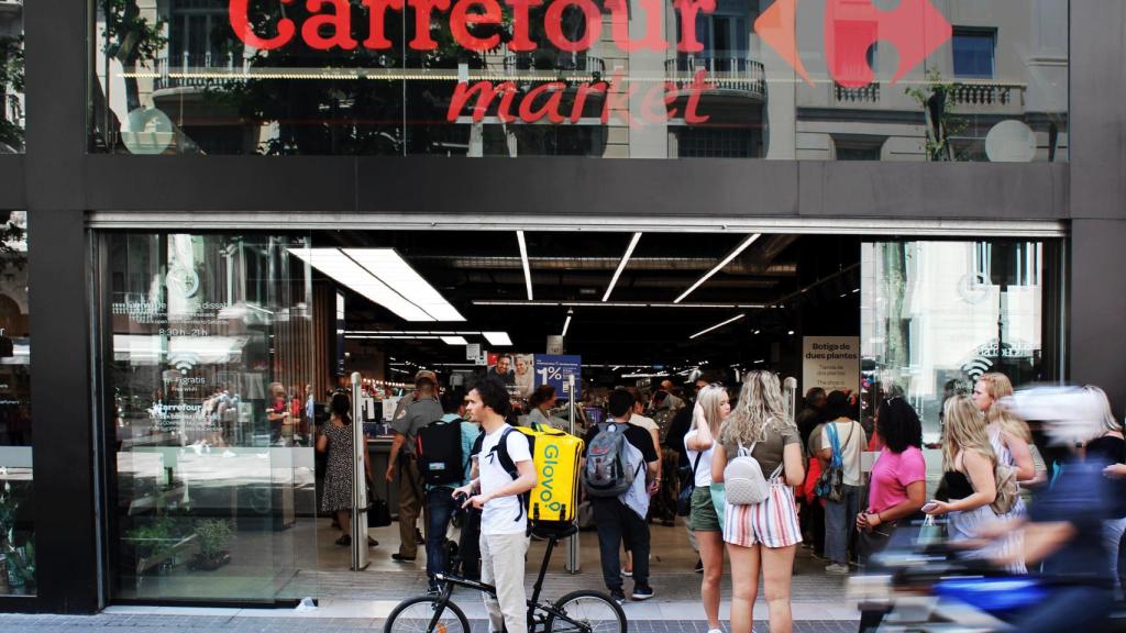 Un rider de Glovo frente a un supermercado Carrefour.