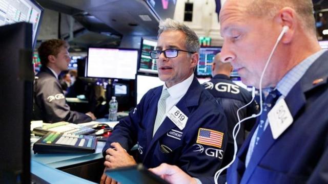 Dos brókeres consultan pantallas en Wall Street.