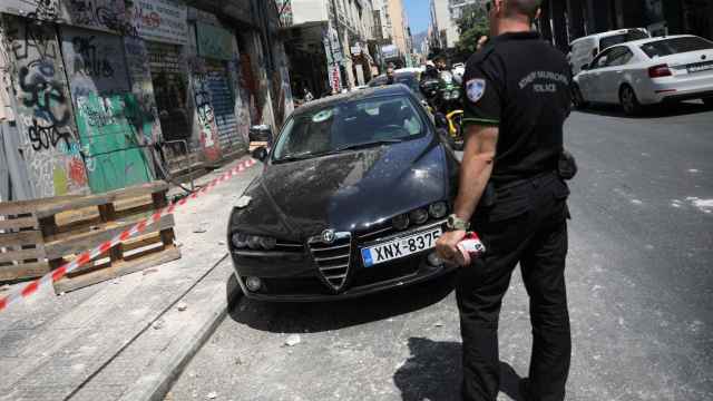 Un policía, junto a un coche dañado por el terremoto que se ha producido este viernes en Atenas.