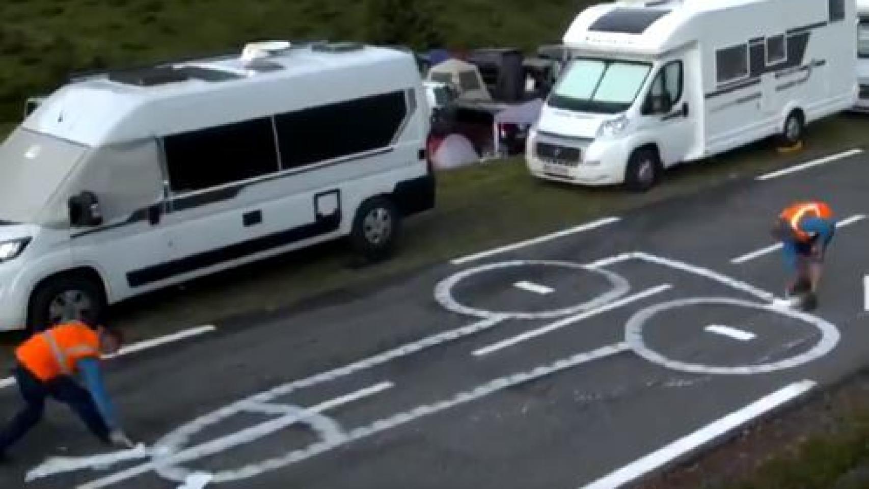 Operarios del Tour limpiando penes dibujados en la carretera