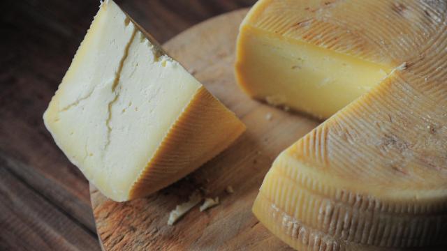 Una cuña de queso cortada sobre una tabla de madera.