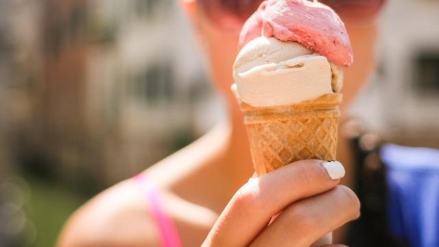 Una joven sostiene un helado de fresa con nata.