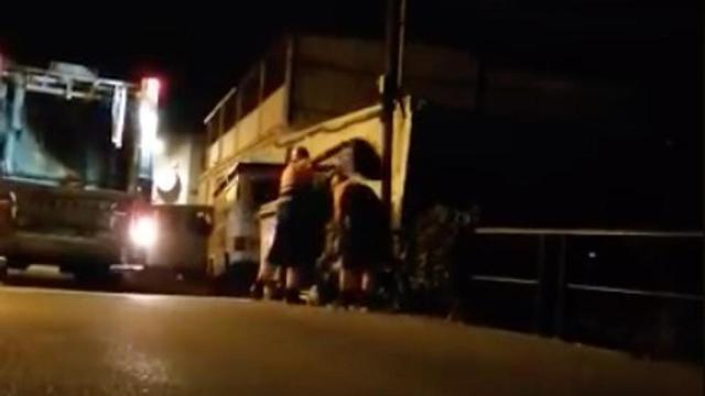 Los dos trabajadores, en plena faena tirando basura al río.