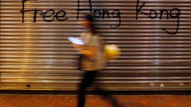 A woman walks past a graffiti during a protest in Hong Kong