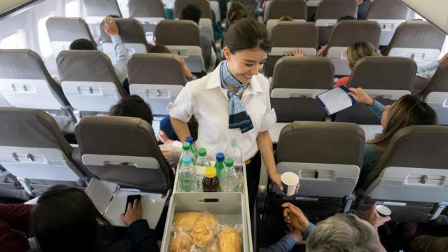 Una azafata atiende a los pasajeros de un avión.