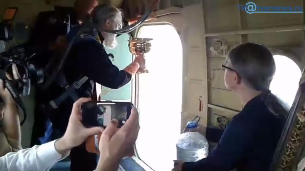 El padre Alexander echa el agua bendita desde el avión.