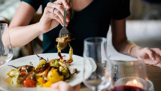 Una joven pinchando en un plato de verdura con un tenedor.