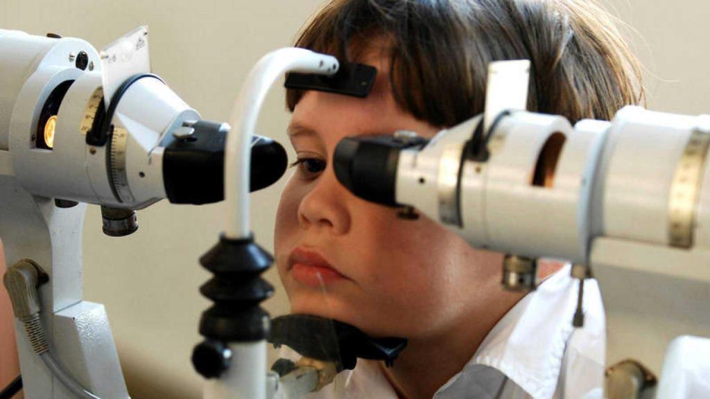 Niño con miopía severa ejercitando la vista con la ayuda de equipo médico