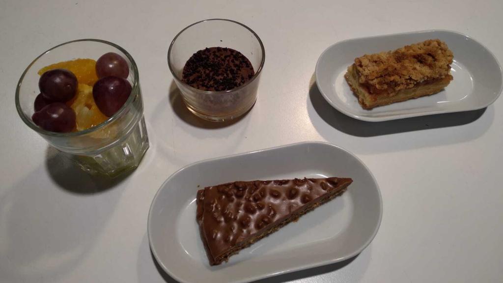 Postres variados: fruta, tarta de chocolate, tarta de manzana y de arándanos.