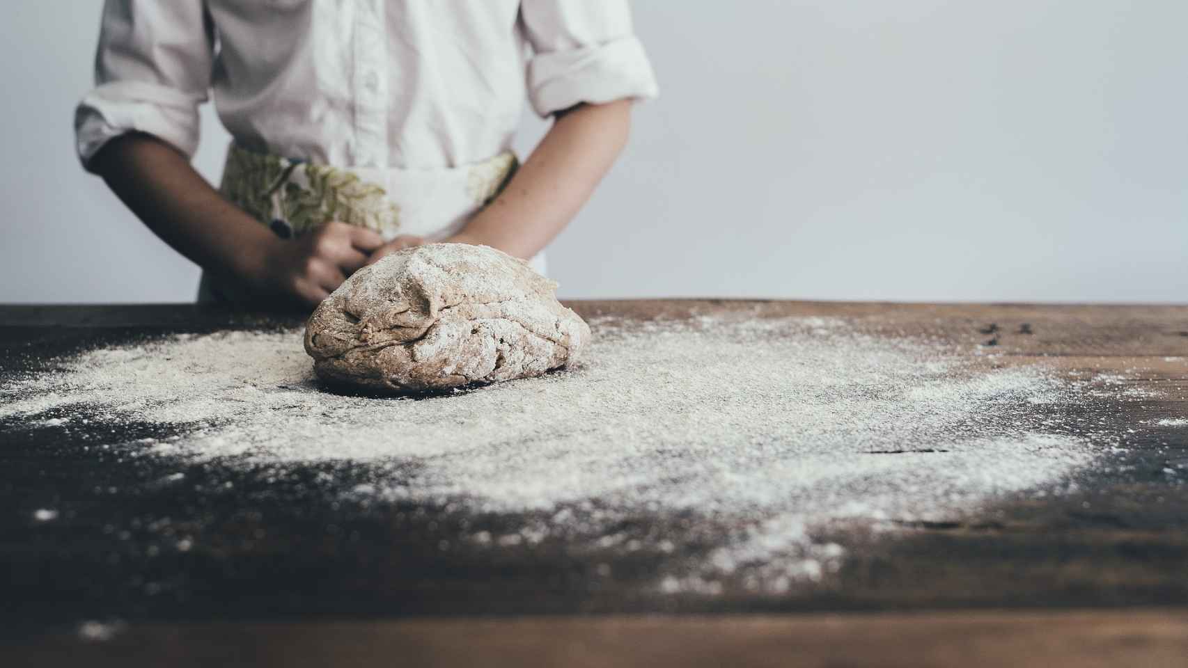 Un panadero amasando un trozo de pan antes de meterlo al horno.
