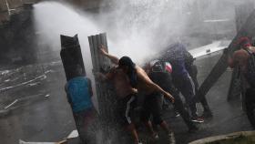 Manifestantes contra un cañón de agua de la Policía en Santiago de Chile