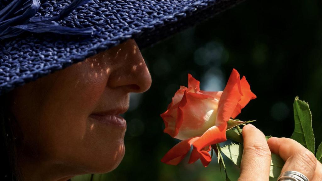 Una mujer huele una flor.