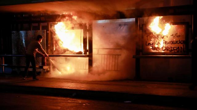 Un hombre trata de sofocar un incendio en las calles de Santiago.