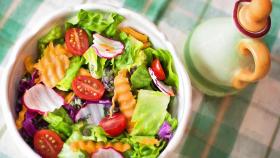 Una ensalada verde elaborada con tomate, rábano y lechuga, entre otras verduras.