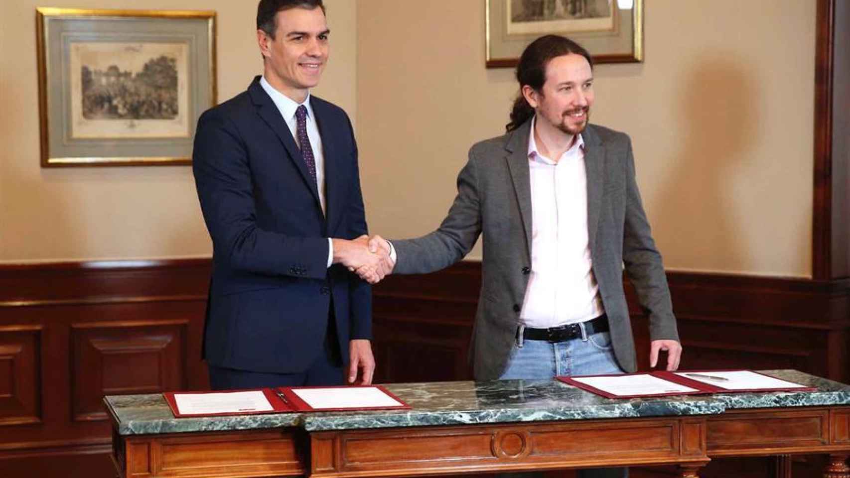 Pedro Sánchez y Pablo Iglesias se estrechan la mano en el Congreso donde han firmado un acuerdo para la formación de un Ejecutivo.