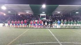 Los jugadores de El Álamo y el Pedroñeras, ante el momento en el que sonó el himno franquista