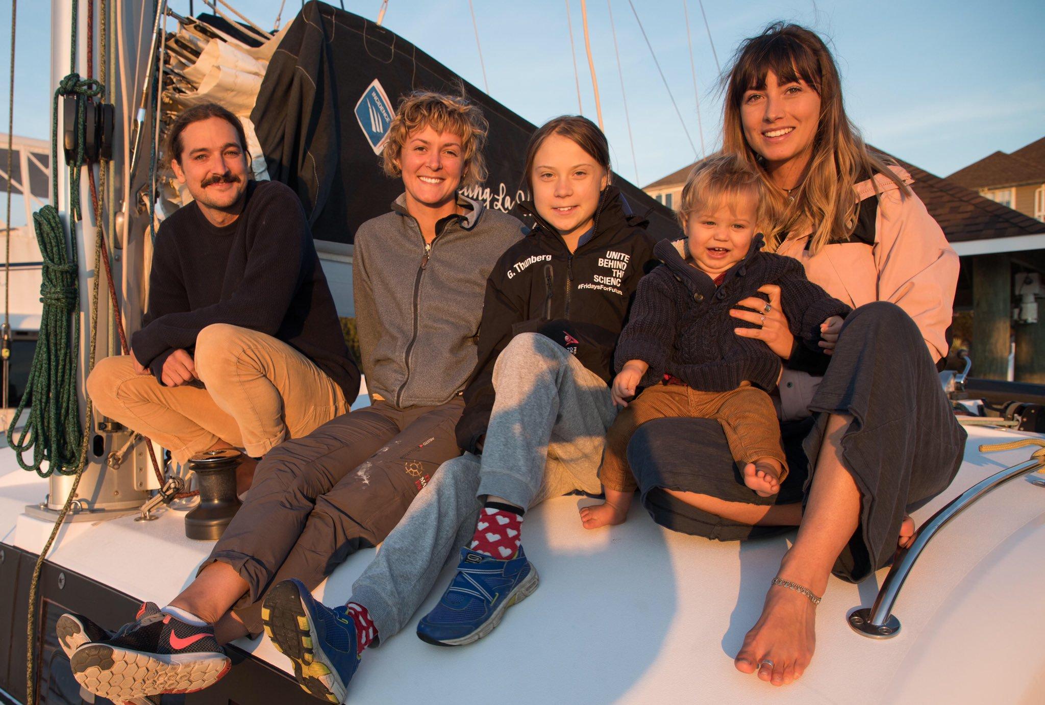 La activista Greta Thunberg, junto a los propietarios del velero que la traerá a España.