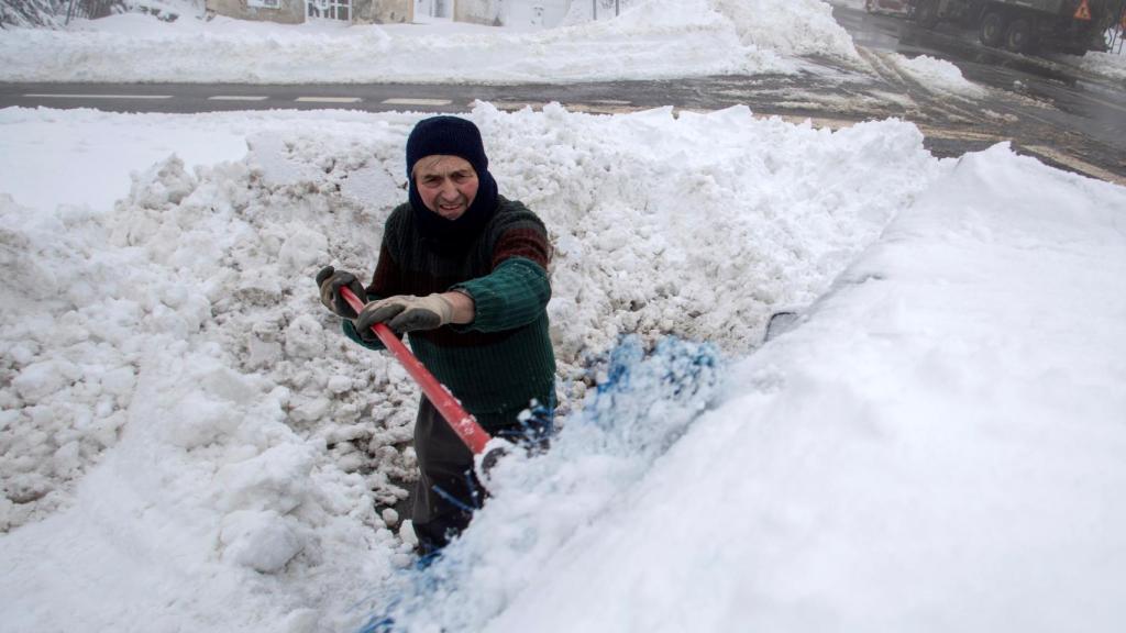 Un hombre retira nieve de su vehículo, este viernes, en el alto del pueblo lucense de O Poio, en Galicia.