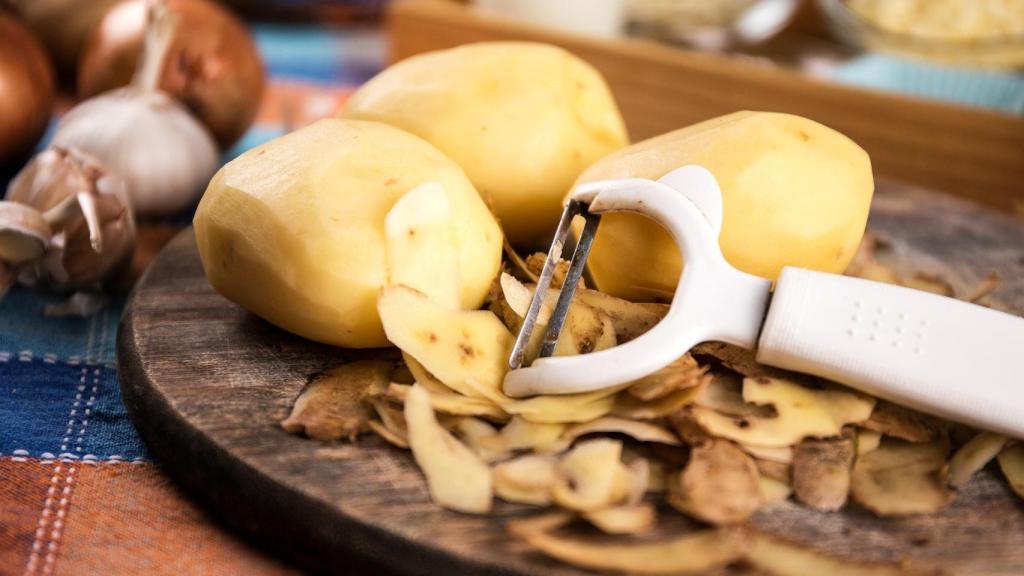 Unas patatas peladas encima de una tabla de madera.