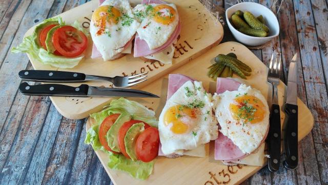 Unas tostadas con huevo, tomate, aguacate y jamón.