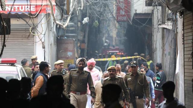 Tres policías caminan entre los escombros de la fábrica que se incendió este domingo en la India.