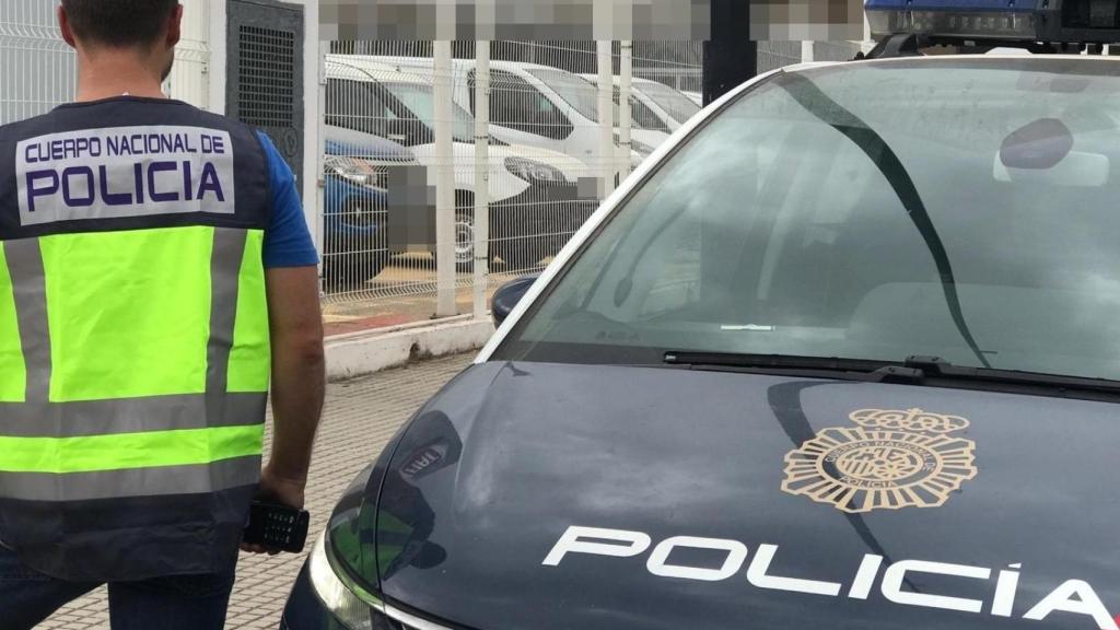 Un agente de Policía Nacional, junto a su coche de intervención.