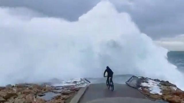 Un ciclista se adentra en una ola en Punta Herminia