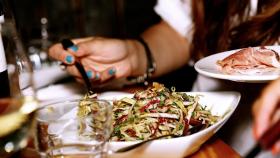 Una mujer degustando un plato de ensalada en un restaurante.