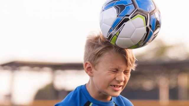 Un niño remata de cabeza un balón de fútbol.