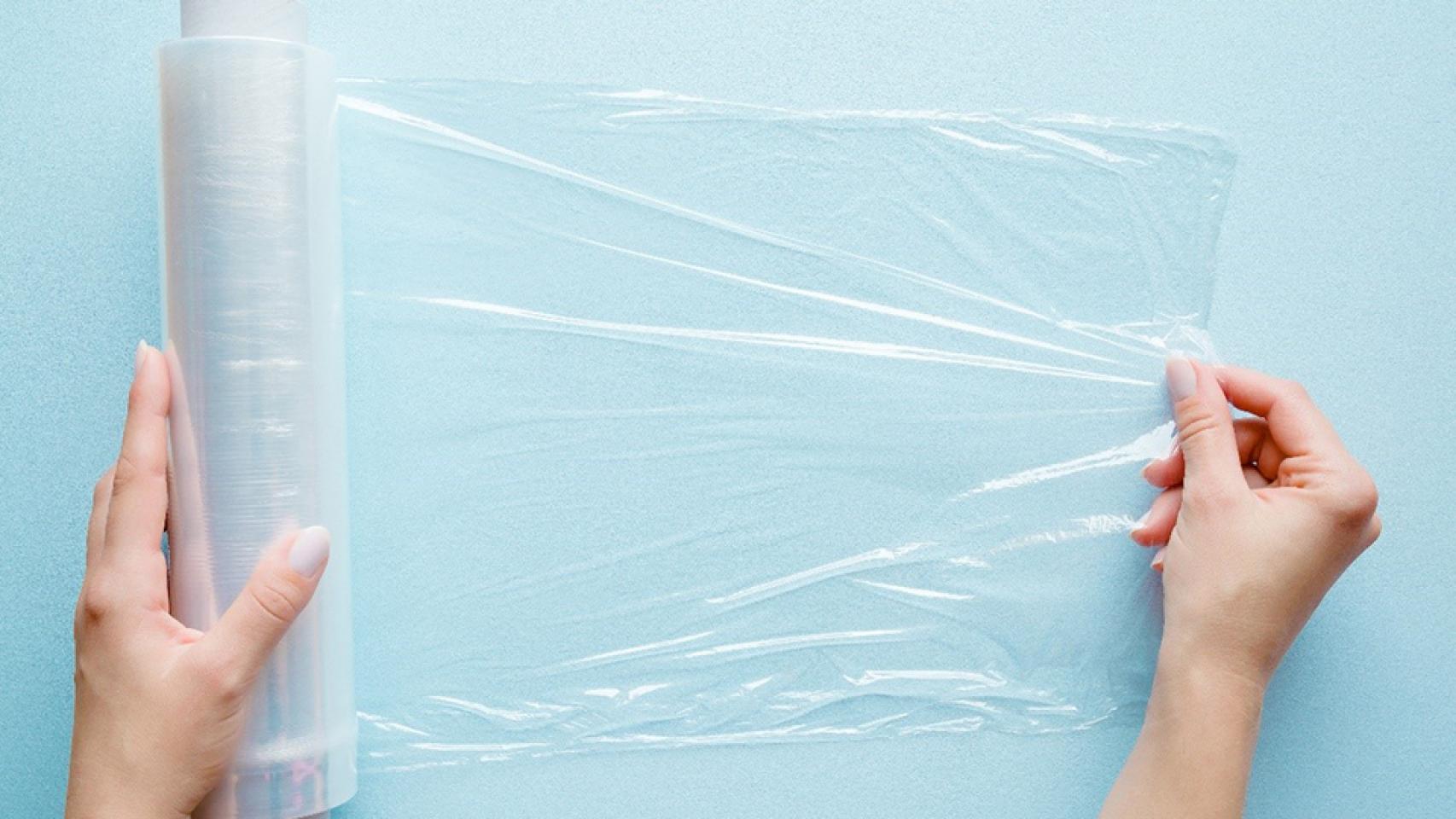 Una mujer desenrollando el papel film de cocina.