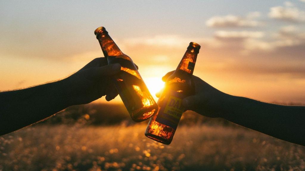 Dos amigos brindan con botellines de cerveza.