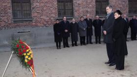 Los Reyes realizan una ofrenda florarl ante el muro de la muerte en Auschwitz.