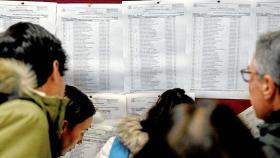 Un grupo de graduados en medicina consulta en las listas el lugar donde realizarán el MIR.