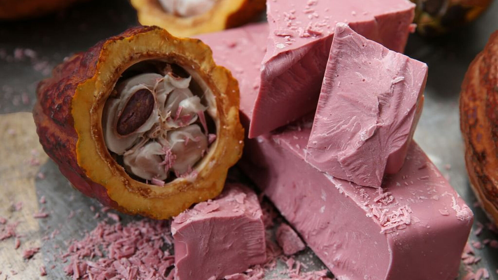 Algunos pedazos de chocolate rubí junto a un grano de cacao.