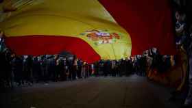 Una gran bandera de España se ha desplegado durante la concentración frente a la Delegación del Gobierno.