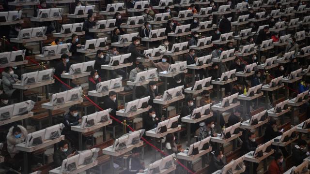 Trabajadores en Kunming, China, con mascarillas y ordenadores cubiertos