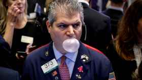 Un bróker hincha una pompa de chicle en la Bolsa de Nueva York.