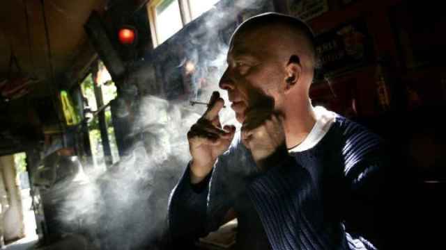 Un hombre fuma un  porro en un coffeeshop.