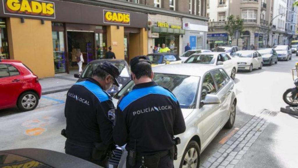 Dos agentes ponen una multa a un coche mal aparcado.