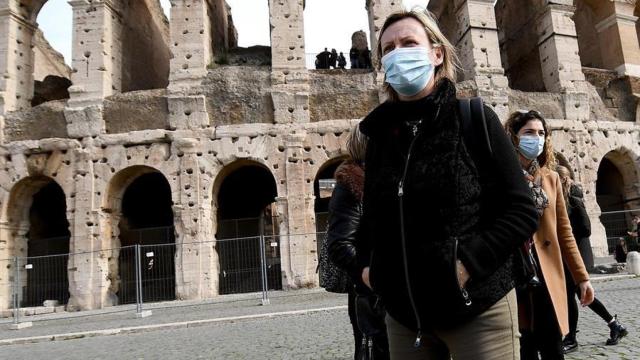 Una joven con mascarilla delante del coliseo romano.