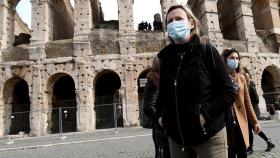 Una joven con mascarilla delante del coliseo romano.