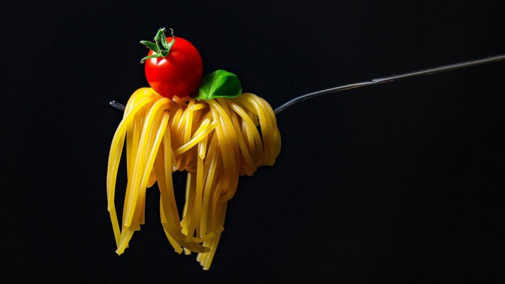 Un tenedor con unos espaguetis y un tomate.