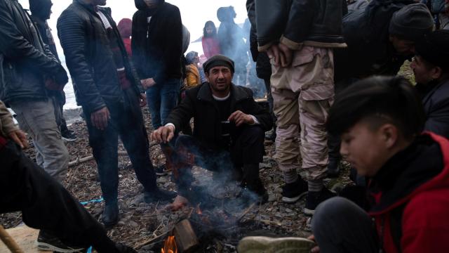 Migrantes se calientan junto a las hogueras después de cruzar parte del Mar Egeo desde Turquía.