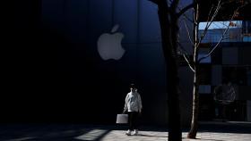 Un hombre con mascarilla pasea delante de una tienda de Apple.