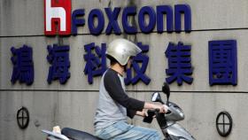 Un motorista pasa por delante de la sede de Foxconn de Taipei.