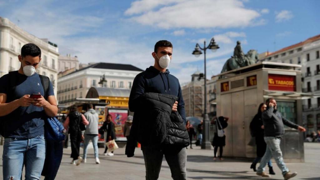 Dos jóvenes caminan con mascarilla por la Puerta del Sol de Madrid.