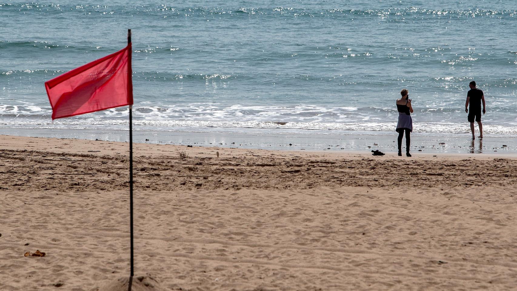 Una pareja disfruta del buen tiempo en una playa de Chiclana de la Frontera.