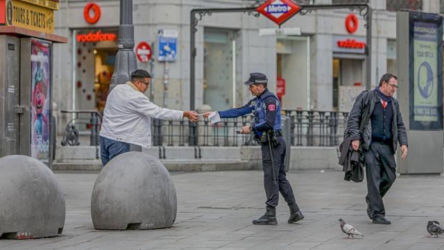 Un policía municipal de Madrid pone una multa a un viandante por no respetar la cuarentena en Madrid.