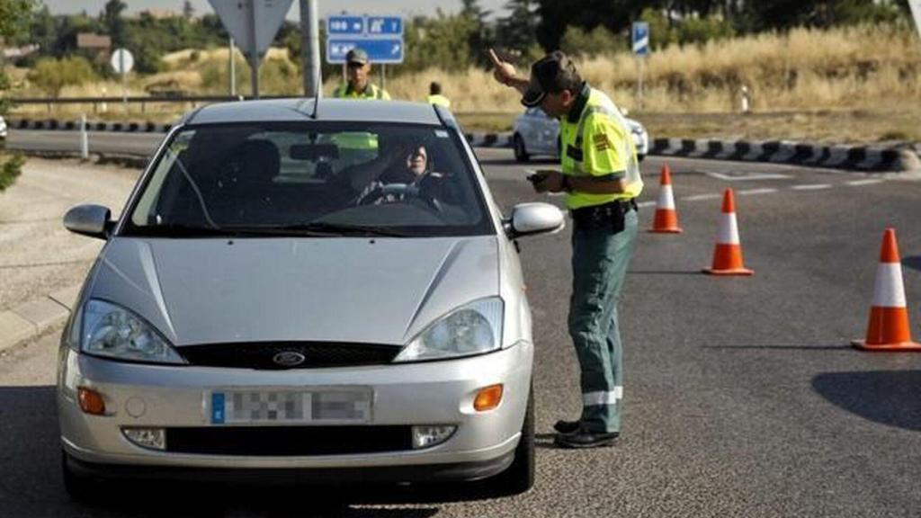 Un agente de la Guardia Civil para a un vehículo en un control.