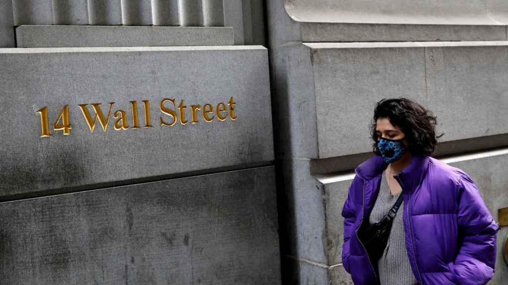 Una mujer con masacarilla pasea por Wall Street.